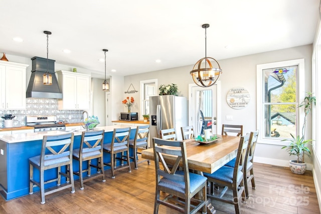 dining space with baseboards, light wood-type flooring, and recessed lighting