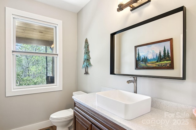 bathroom featuring toilet, baseboards, and vanity