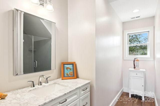 bathroom with visible vents, vanity, baseboards, and wood finished floors