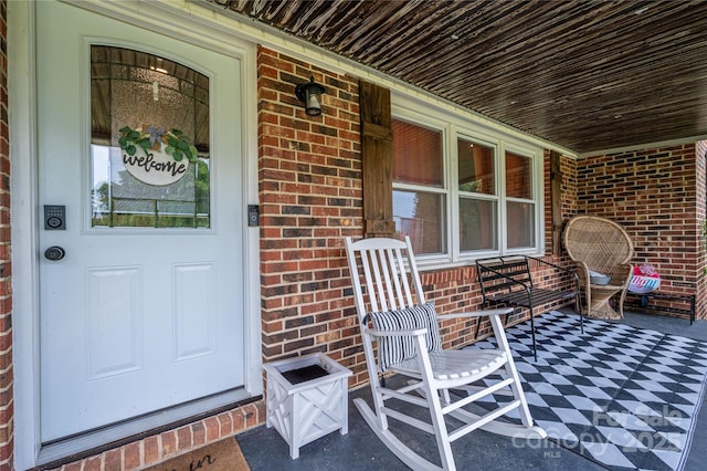 entrance to property featuring covered porch and brick siding