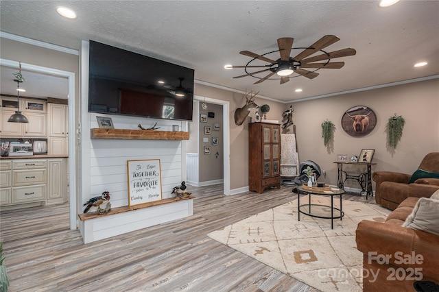 living area featuring light wood-type flooring, crown molding, a textured ceiling, and recessed lighting