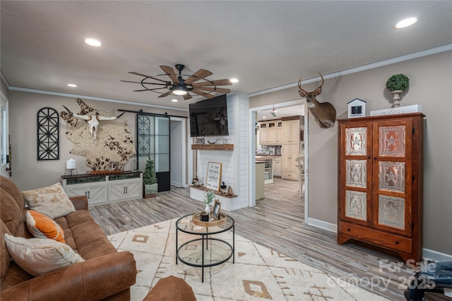 living room with light wood-style floors, a barn door, and crown molding