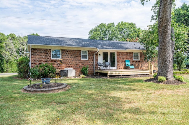 back of house featuring brick siding, roof with shingles, a lawn, central AC, and a deck