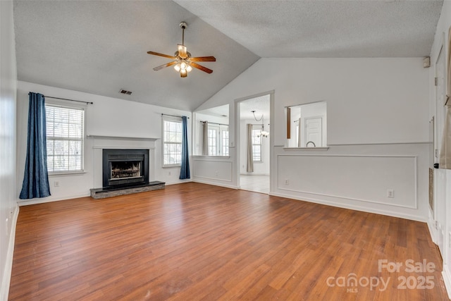 11000 White Stag Dr, Charlotte, NC 28269 - unfurnished living room featuring ceiling fan, wood finished floors, a fireplace with raised hearth, a textured ceiling, and healthy amount of natural light