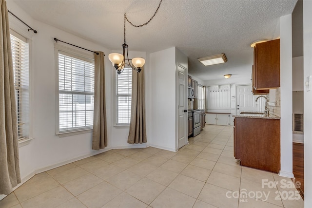 11000 White Stag Dr, Charlotte, NC 28269 - kitchen featuring a chandelier, stainless steel appliances, a textured ceiling, light tile patterned flooring, and brown cabinets