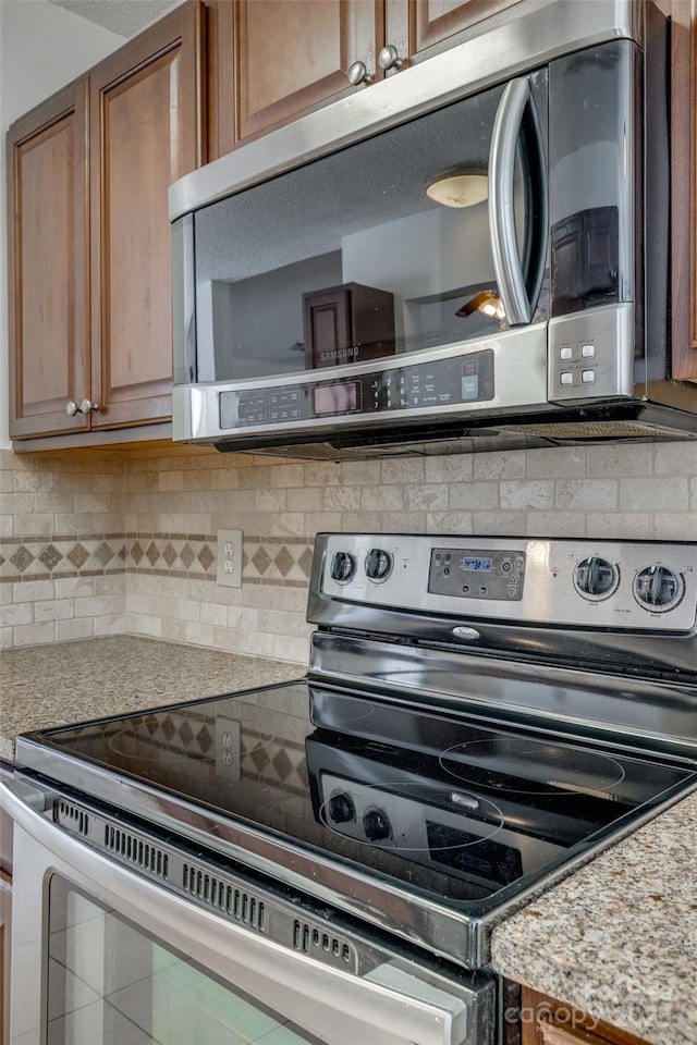 11000 White Stag Dr, Charlotte, NC 28269 - kitchen with stainless steel appliances, tasteful backsplash, and brown cabinetry