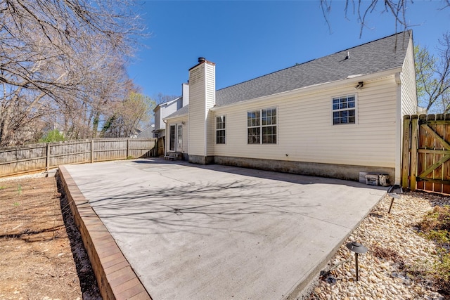 11000 White Stag Dr, Charlotte, NC 28269 - back of property featuring a patio area, a fenced backyard, a chimney, and roof with shingles