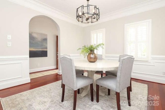 dining room featuring a wainscoted wall, crown molding, and wood finished floors