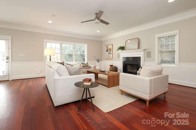 living room with ornamental molding, a fireplace, wainscoting, and wood finished floors