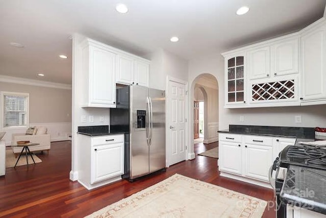 kitchen featuring arched walkways, dark wood-style flooring, stainless steel fridge with ice dispenser, and gas stove