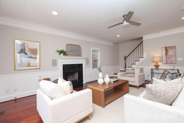 living area with ornamental molding, a fireplace, stairway, and wood finished floors