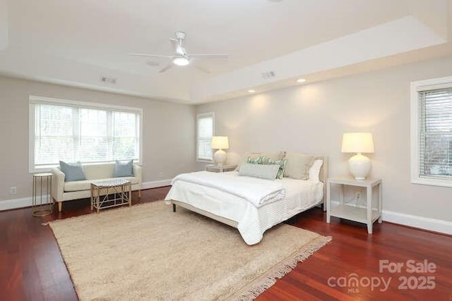 bedroom with baseboards, a raised ceiling, radiator, ceiling fan, and wood finished floors