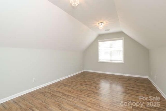 additional living space with vaulted ceiling, wood finished floors, and baseboards