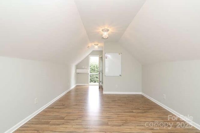 additional living space featuring vaulted ceiling, baseboards, and wood finished floors