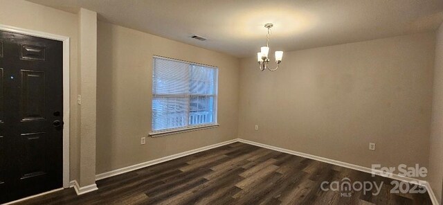 unfurnished room featuring a chandelier, dark wood-style flooring, and baseboards