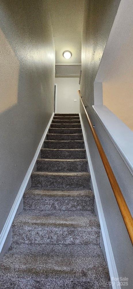 stairway featuring carpet flooring, a textured ceiling, and baseboards