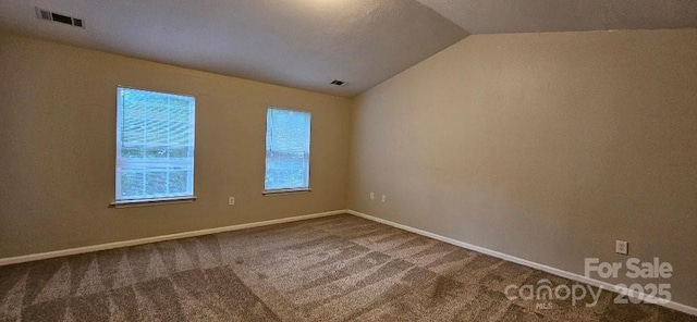 unfurnished room featuring dark carpet, vaulted ceiling, and baseboards