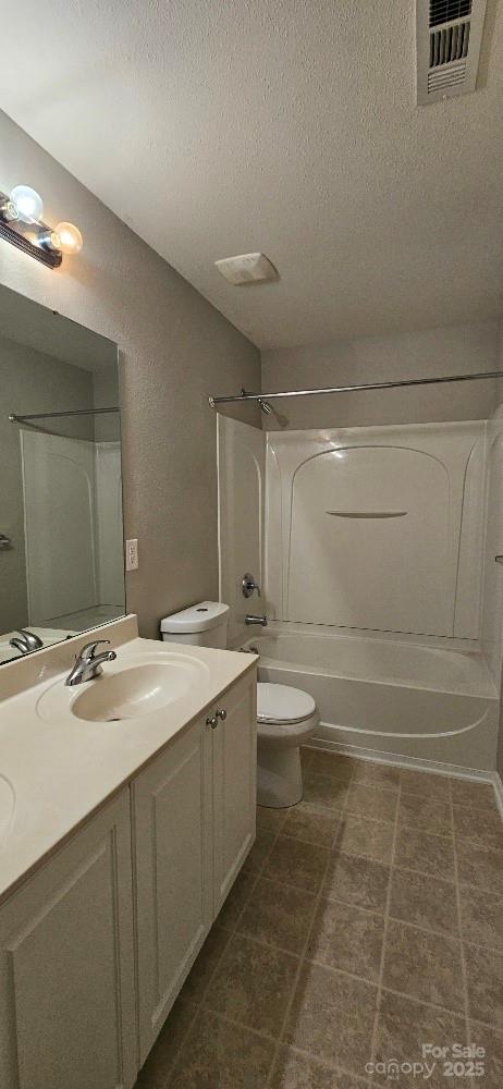 bathroom with toilet, a textured ceiling, bathing tub / shower combination, and vanity