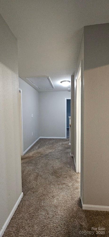 corridor with attic access, carpet floors, and baseboards