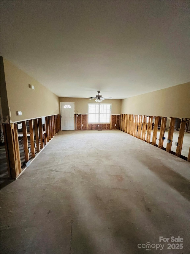 unfurnished living room with ceiling fan and concrete floors