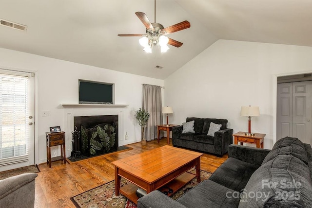 living room featuring visible vents, ceiling fan, wood finished floors, vaulted ceiling, and a fireplace