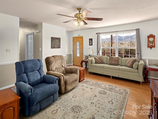 living room featuring a textured ceiling, a ceiling fan, and light wood-style floors