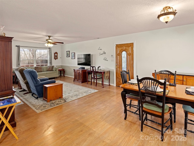 dining space featuring a textured ceiling, ceiling fan, and light wood-style floors