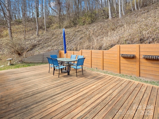 wooden terrace featuring outdoor dining area and a fenced backyard