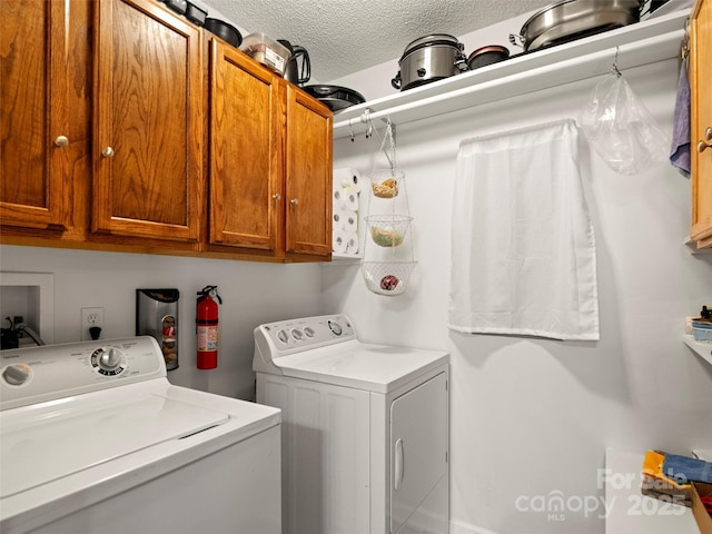 laundry room featuring cabinet space, a textured ceiling, and washing machine and clothes dryer