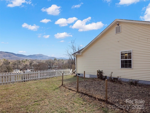 view of home's exterior with a lawn, fence, and a mountain view