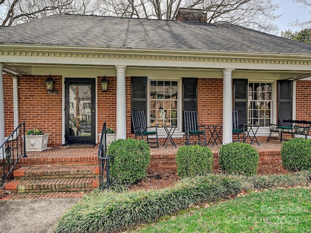 view of exterior entry with a porch and brick siding