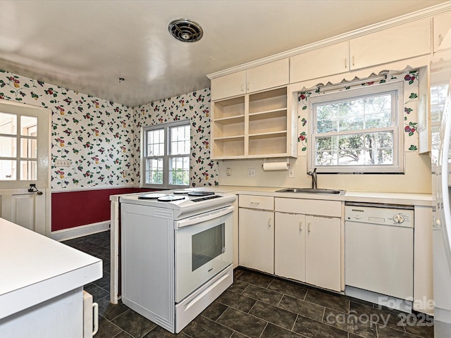 kitchen with white appliances, light countertops, a sink, and wallpapered walls