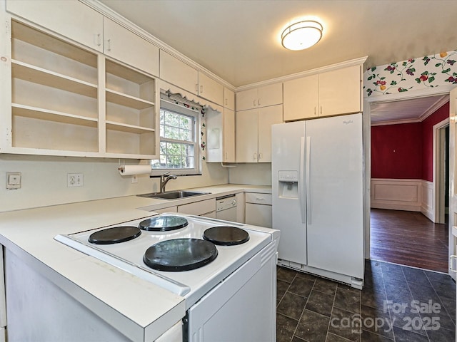 kitchen with white appliances, a wainscoted wall, ornamental molding, light countertops, and a sink