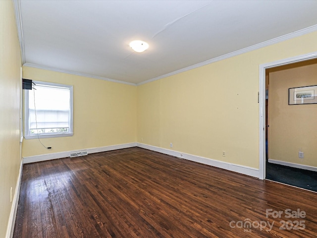 spare room featuring dark wood-style floors, baseboards, visible vents, and crown molding