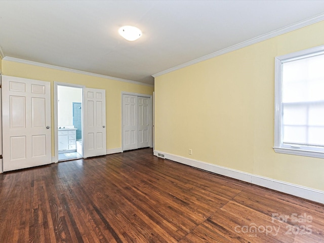 unfurnished bedroom featuring dark wood-style floors, connected bathroom, ornamental molding, and baseboards