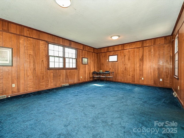 unfurnished room featuring a textured ceiling, dark carpet, visible vents, and baseboards