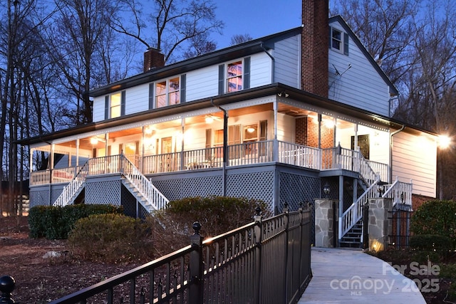 view of front of property featuring stairs, a porch, a chimney, and brick siding