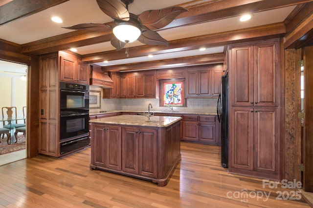 kitchen featuring light wood finished floors, decorative backsplash, black appliances, beam ceiling, and a warming drawer