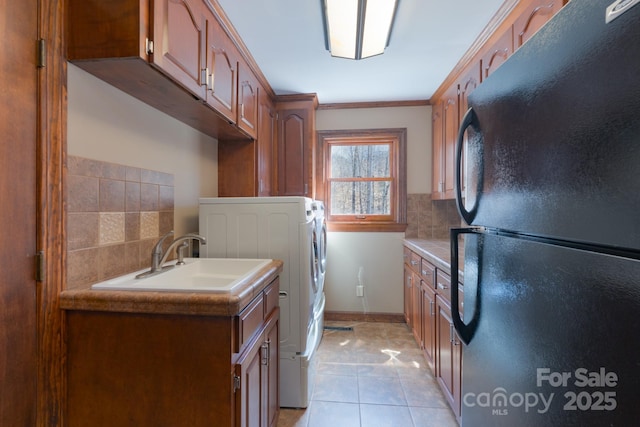 laundry room with crown molding, washer / clothes dryer, light tile patterned flooring, a sink, and baseboards