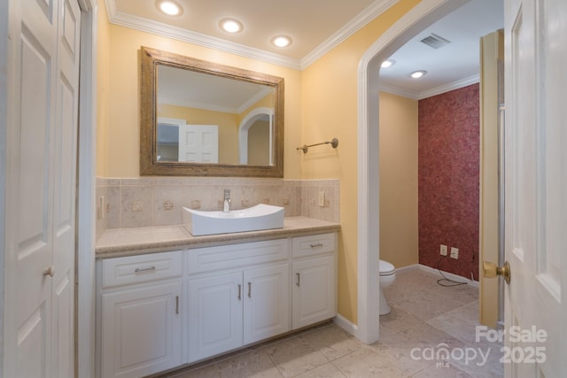 bathroom with crown molding, visible vents, toilet, vanity, and baseboards