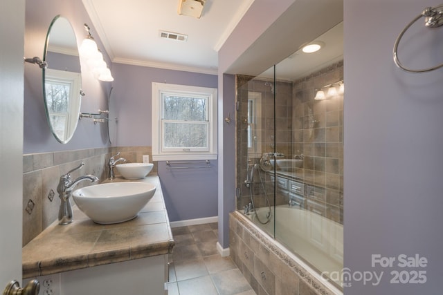 bathroom featuring crown molding, visible vents, a sink, and tiled shower / bath combo