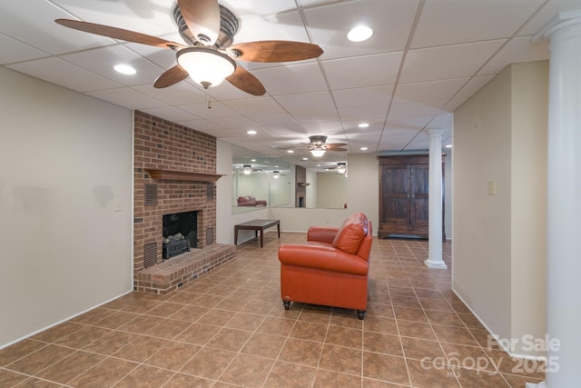 living area featuring a paneled ceiling, ornate columns, a fireplace, and tile patterned floors