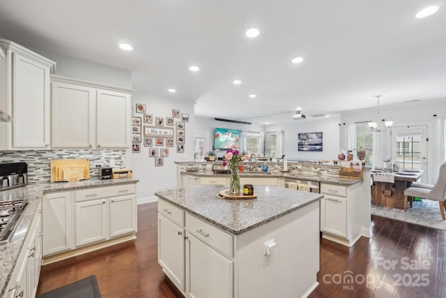 kitchen with a center island, stainless steel appliances, decorative backsplash, dark wood-type flooring, and white cabinetry