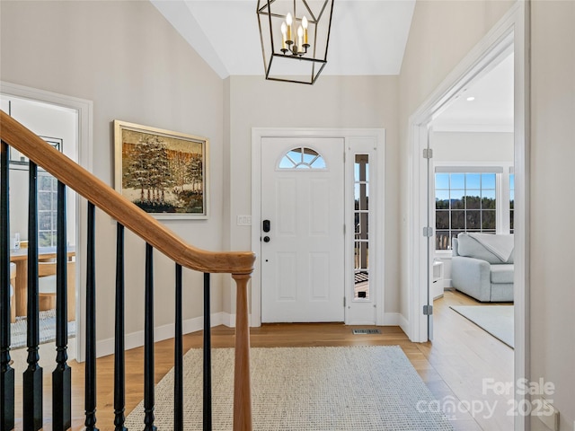 entrance foyer featuring stairs, wood finished floors, baseboards, and a chandelier