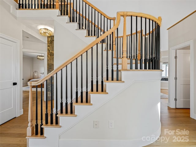 stairway featuring a towering ceiling and wood finished floors