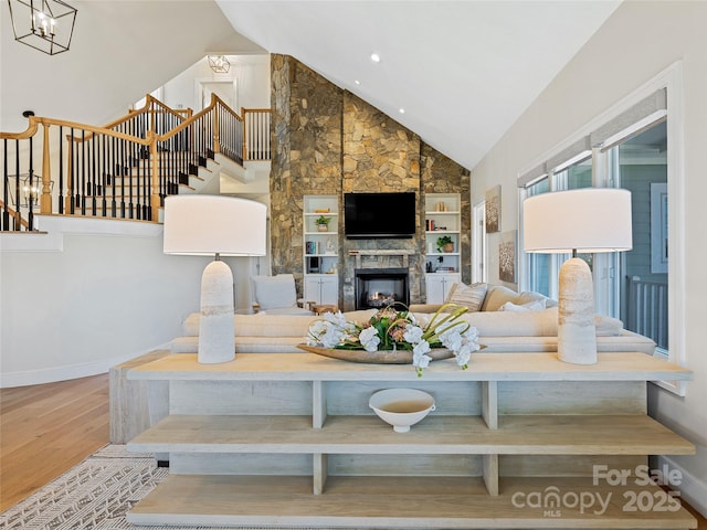 living room with baseboards, stairway, a fireplace, wood finished floors, and high vaulted ceiling