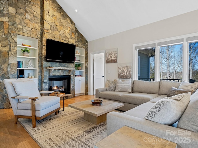 living area featuring wood finished floors, a fireplace, and high vaulted ceiling