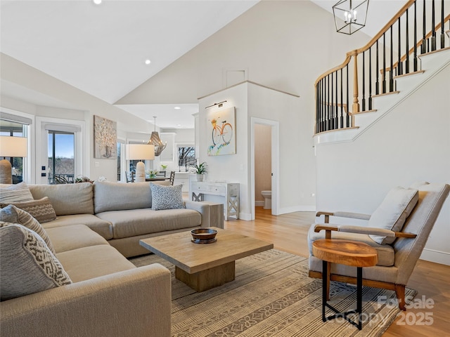 living area featuring stairway, baseboards, an inviting chandelier, and light wood finished floors