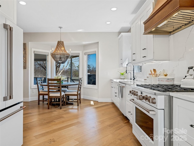 kitchen featuring custom exhaust hood, light countertops, premium appliances, and a sink