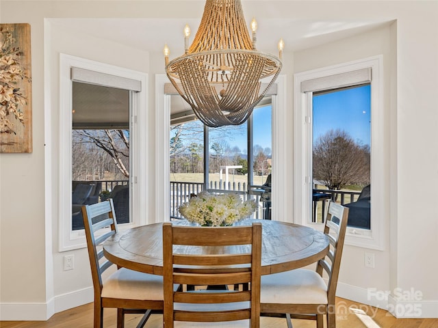 dining area with baseboards, a notable chandelier, and wood finished floors